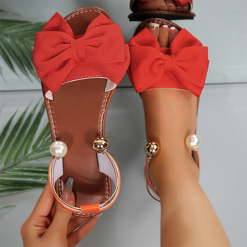 Moda veraniega: sandalias planas chic mujer con lazo decorativo y perlas brillantes.