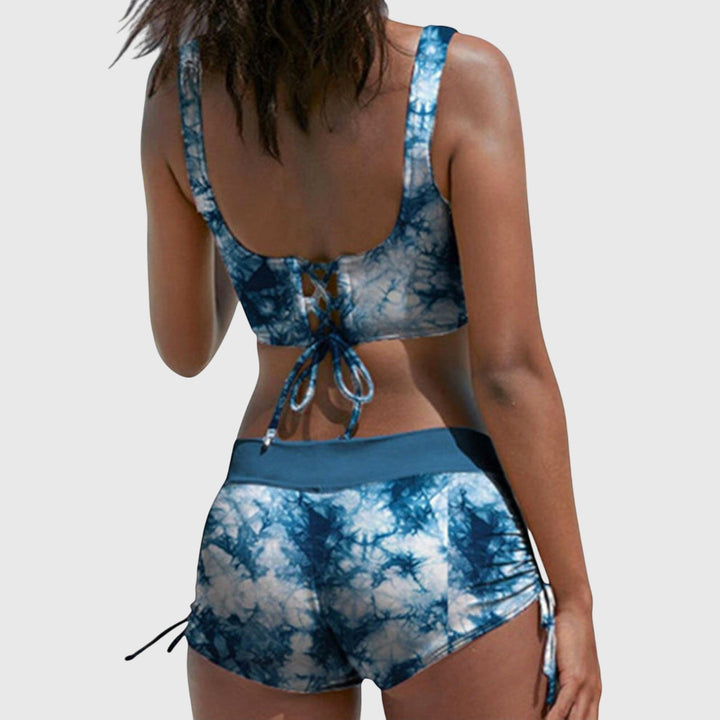 Mujer vistiendo bikini de camuflaje deportivo. Conjunto dos piezas con top cruzado y shorts fruncidos para el verano.