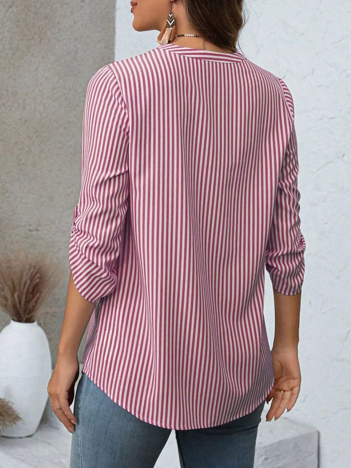 Blusa de rayas blancas y negras, cuello V, manga enrollable, ideal para un look monocromático.