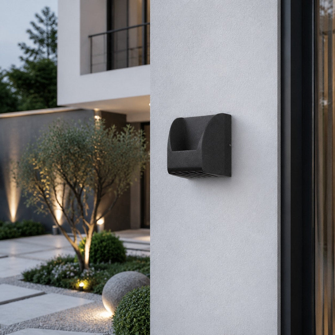 Aplique LED negro de estilo industrial, ideal para iluminación exterior direccional en patios y jardines.