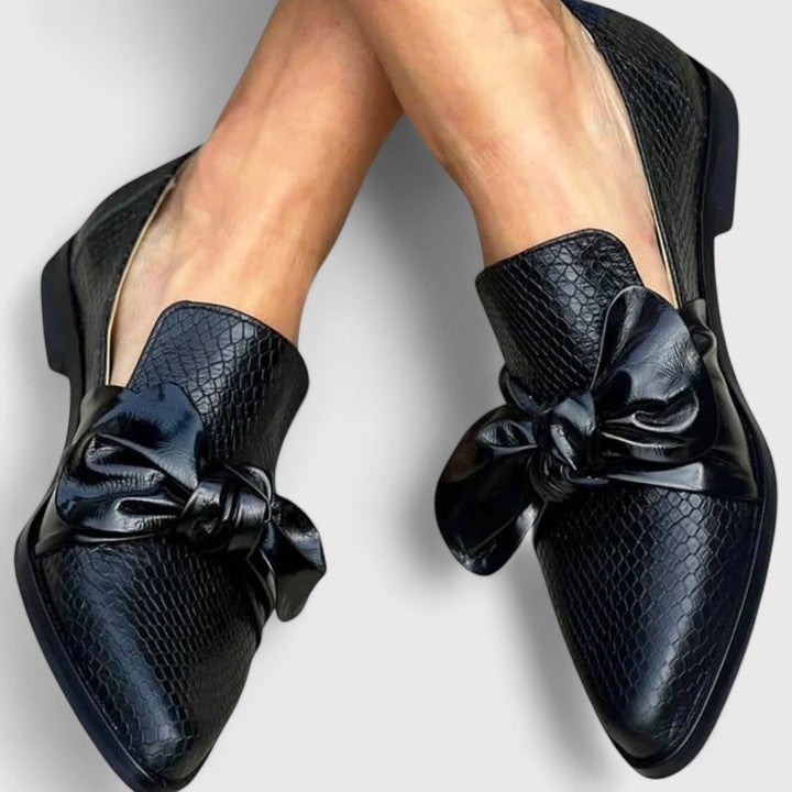 Mocasines negros elegantes de mujer con lazo decorativo. Calzado femenino chic y cómodo sin cordones.