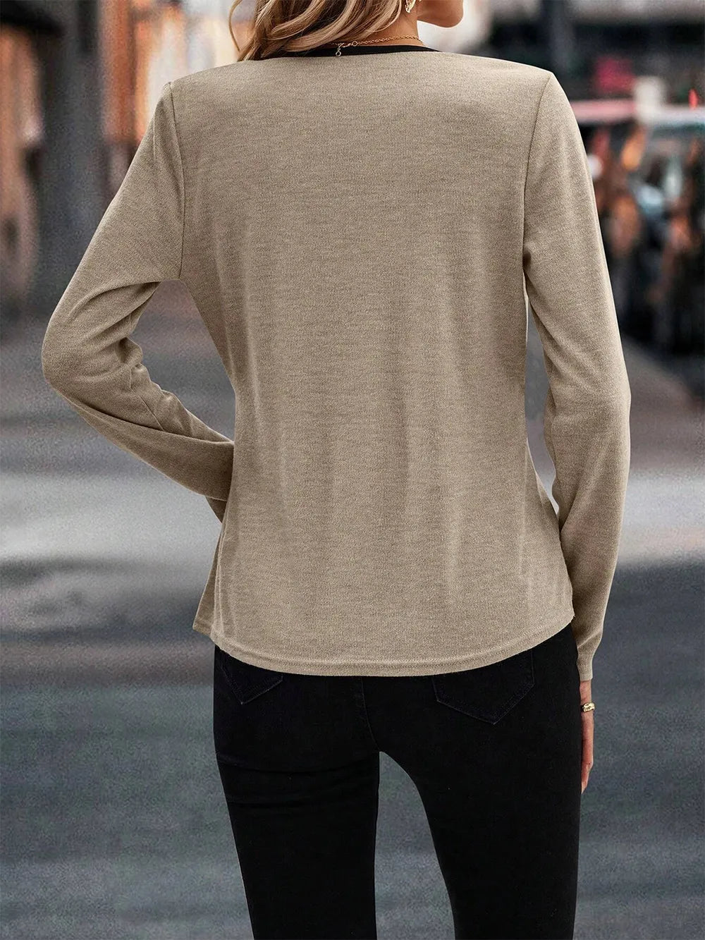 Camiseta elegante mujer, manga larga, destacando su escote cruzado con ribete de contraste. Estilo moderno.