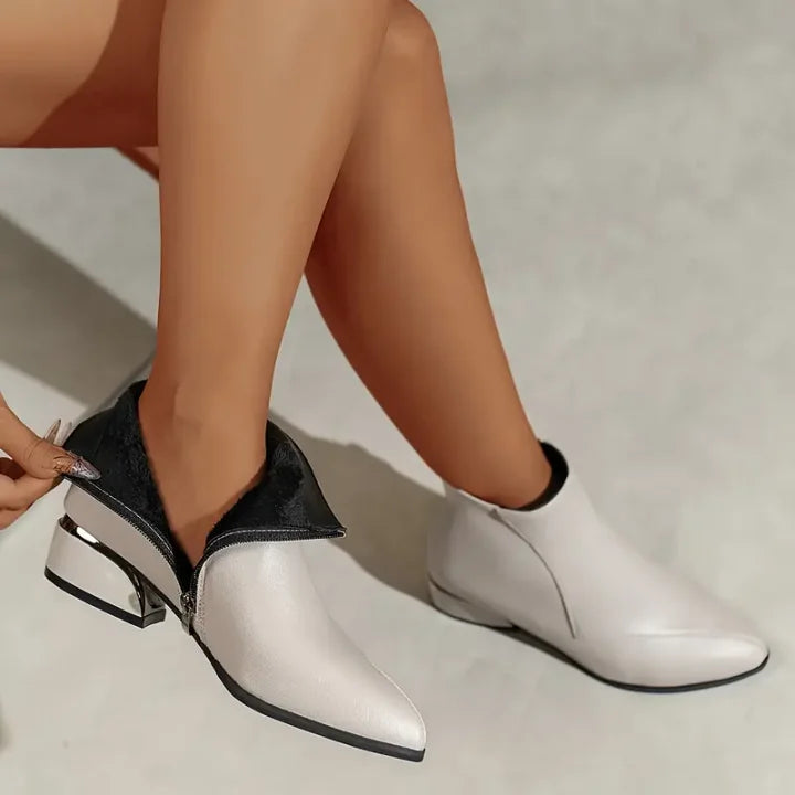 Perfil de botines de mujer con tacón bajo, punta estilizada y cremallera lateral práctica.