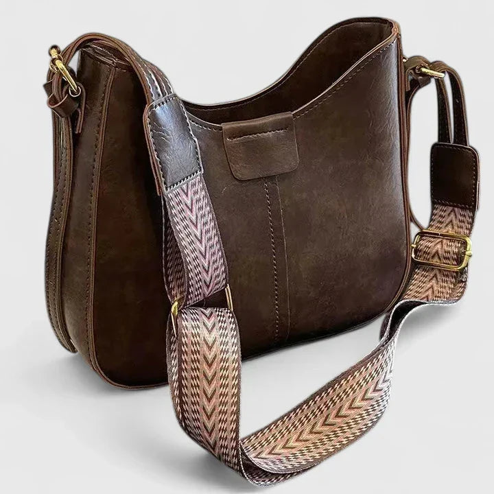 Elegante bolso bandolera de piel para mujer con herrajes dorados y correa ajustable.