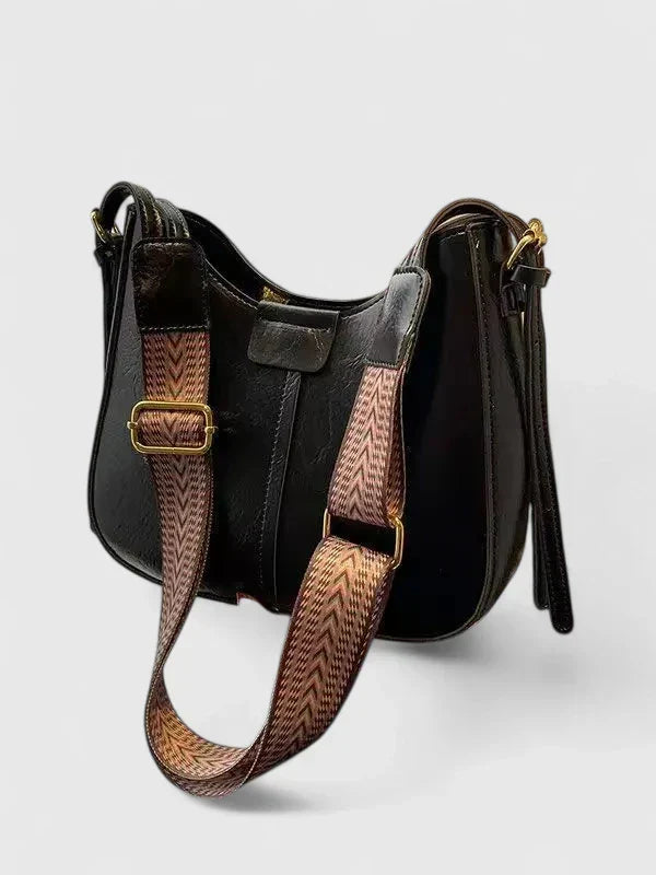 Primer plano de bolso bandolera de piel para mujer, destacando herrajes dorados y textura.