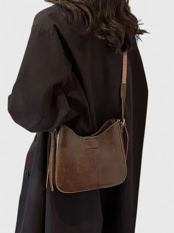 Mujer luciendo bolso bandolera de piel con correa ajustable, estilo casual y elegante.