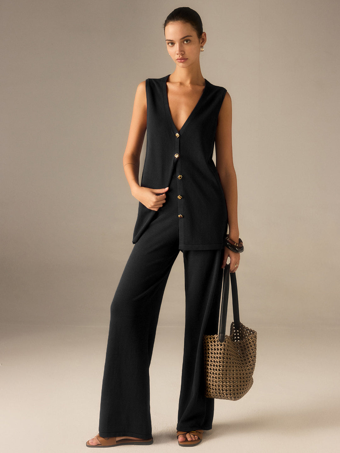 Mujer luciendo conjunto de chaleco y pantalones anchos, look sofisticado con botones dorados.