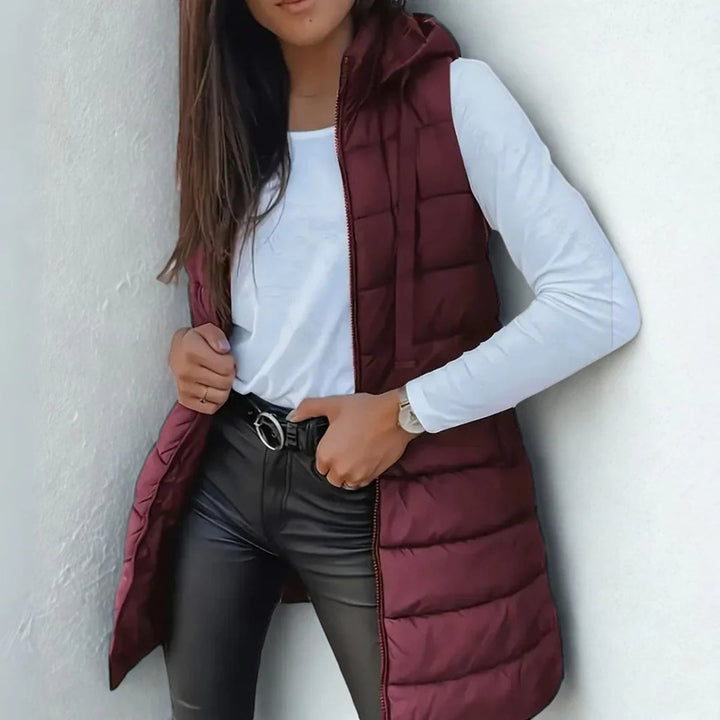 Chaleco largo de mujer con capucha y acolchado. Diseño elegante y cómodo para el frío invernal.