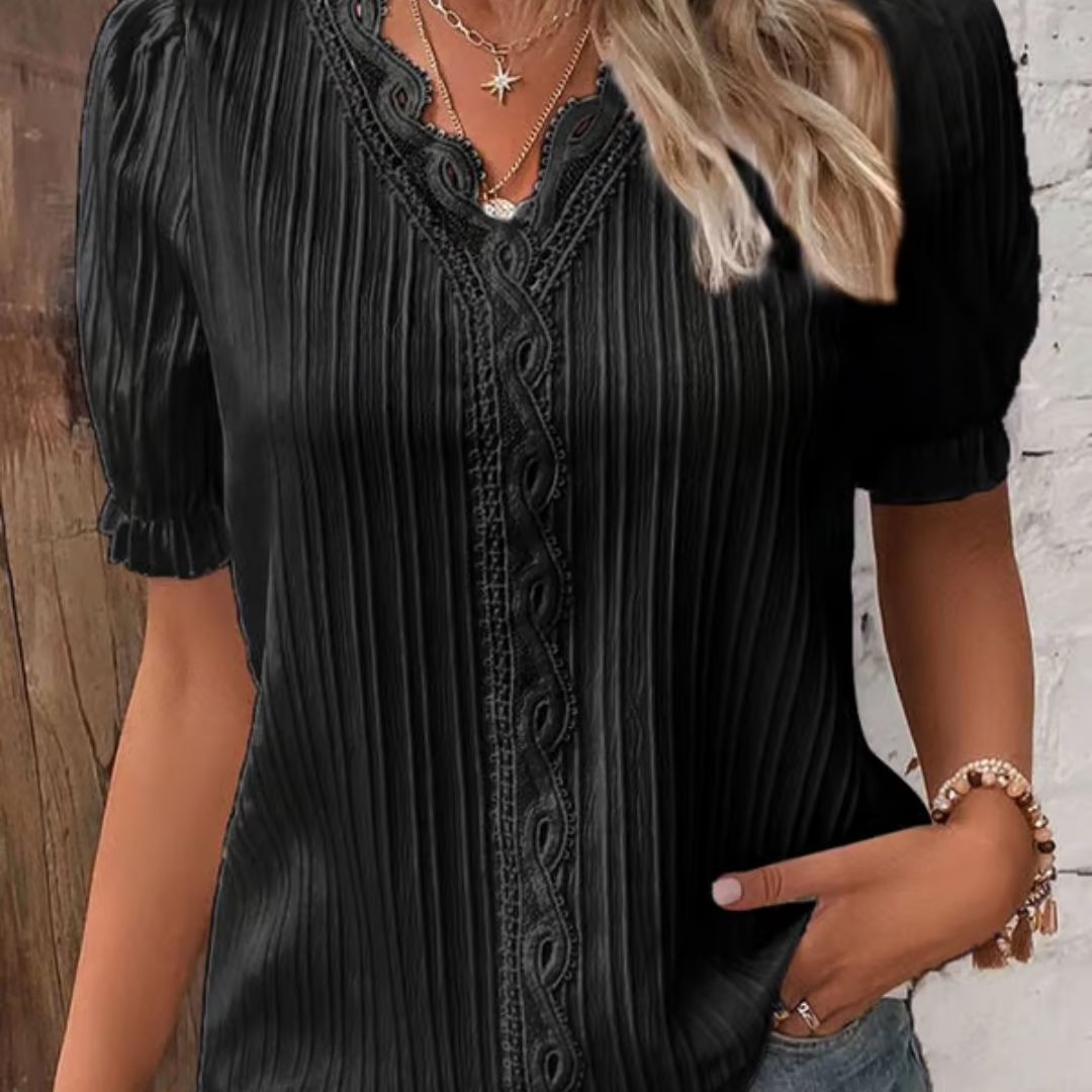 Mujer modelando blusa de encaje sofisticada. Escote en V y manga larga para un look elegante.