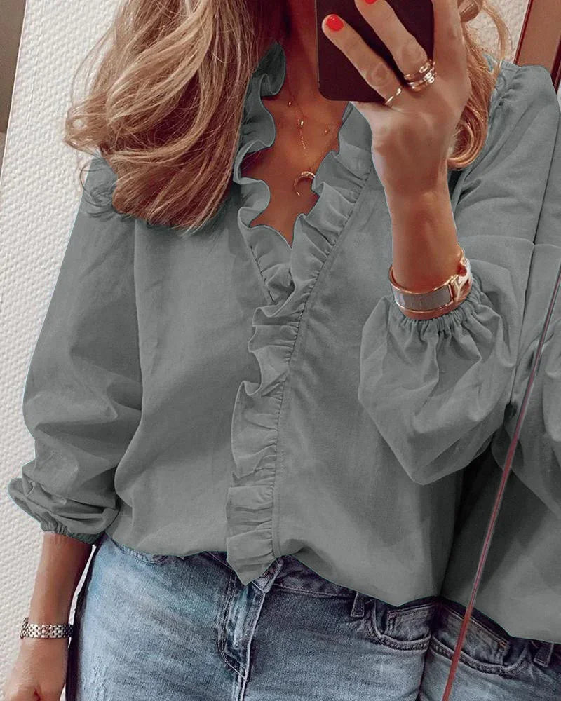 Blusa holgada de volantes con manga larga para mujer. Cuello V y estilo casual moderno.