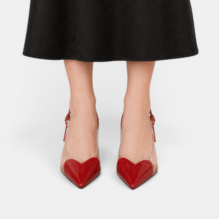 Moda femenina: tacones transparentes con tacón de aguja y adorno de corazón. Zapatos elegantes.