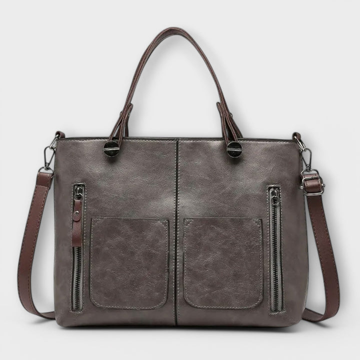 Bolso tote negro con cremallera y bolsillos internos, accesorio de moda elegante para mujer.