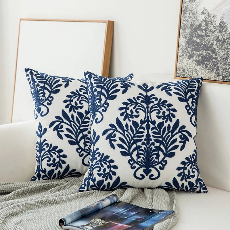 Detalle de cojín azul con bordado geométrico abstracto. Textil decorativo premium para sala y hogar.