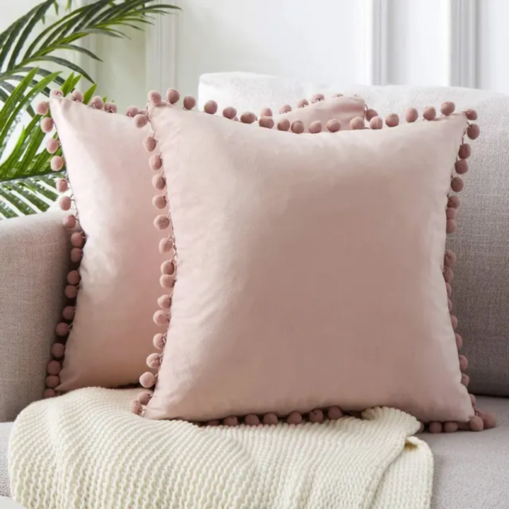 Cojín decorativo estilo bohemio con pompones. Suave y texturizado, aporta calidez y confort a cualquier espacio del hogar.