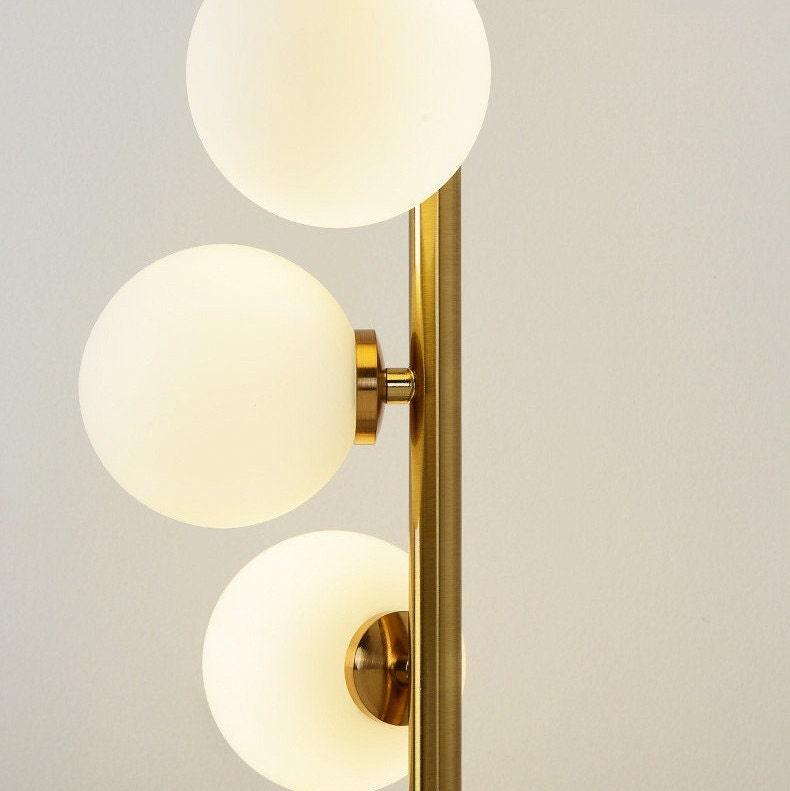 Lámpara de pie de lujo con acabados en latón dorado y pantallas de ópalo. Ideal para diseño de interiores moderno.