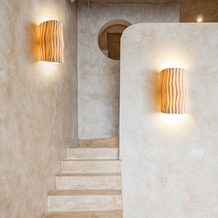 Aplique de pared de resina acanalada con luz encendida, destacando su iluminación moderna.
