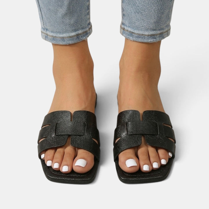 Detalle de la tira en H de sandalias planas ortopédicas para mujer, combinando estilo moderno y soporte seguro.