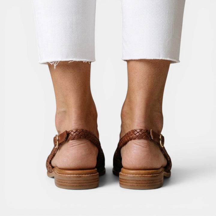Sandalias planas trenzadas de mujer con punta cerrada. Estilo veraniego casual, moda femenina cómoda.