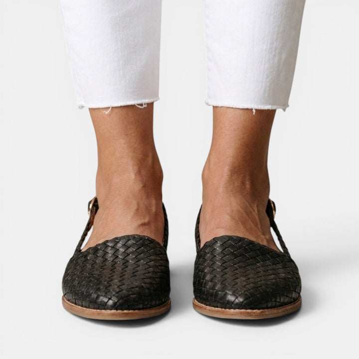 Mujer luciendo sandalias planas trenzadas. Calzado de verano cómodo y de moda femenina casual.