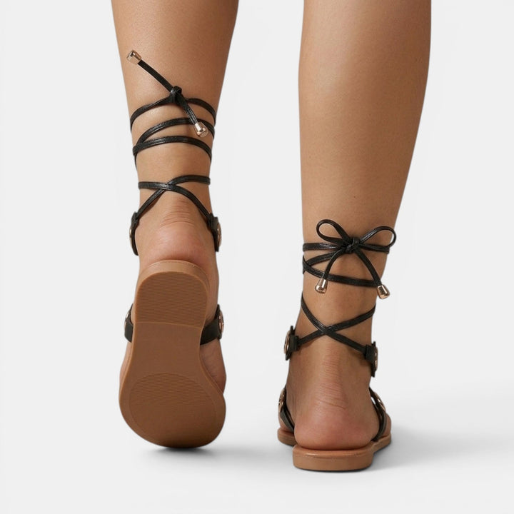 Sandalias planas romanas de mujer, vista trasera. Calzado de verano elegante y cómodo con tiras.