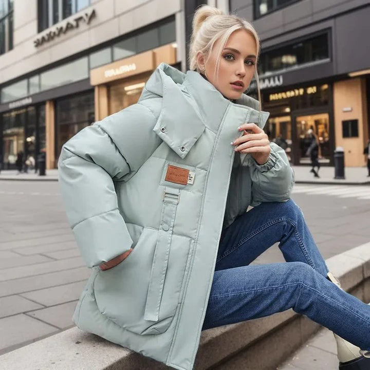 Mujer usando abrigo de nieve REIKA negro, cálido, impermeable y elegante. Ideal para actividades invernales.