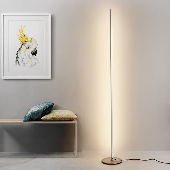 Lámpara de pie LED de diseño minimalista con base circular, ideal para iluminación moderna en dormitorio o sala.