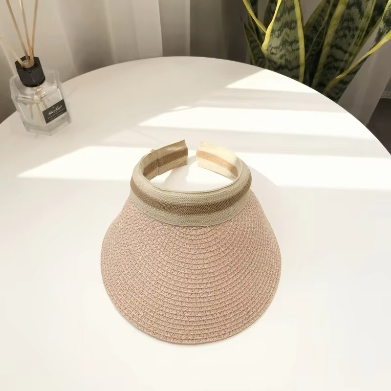 Primer plano de sombrero visera de paja natural con ala ancha, protección UV y cierre ajustable.
