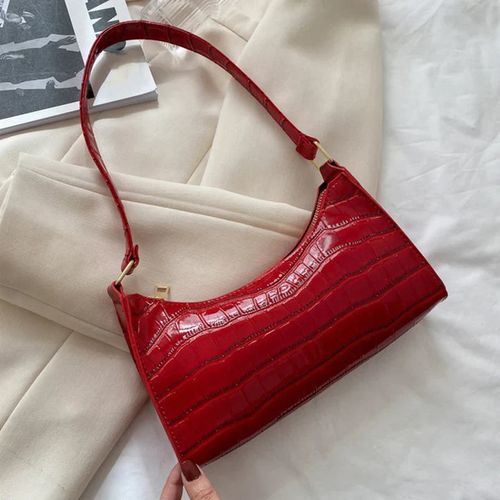 Cartera de mujer de piel de cocodrilo brillante, accesorio de moda chic.