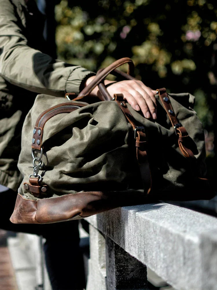 Primer plano de la textura de lona resistente al agua y detalles de cuero en bolso de viaje unisex.