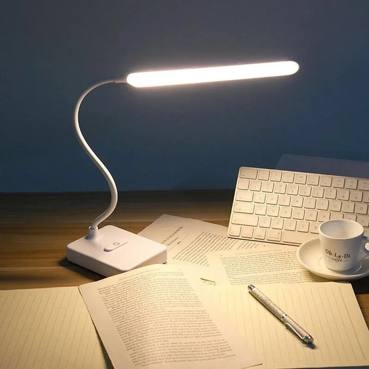 Lámpara LED recargable con protección ocular para lectura. Iluminación regulable, USB, con práctico soporte para móvil en escritorio.