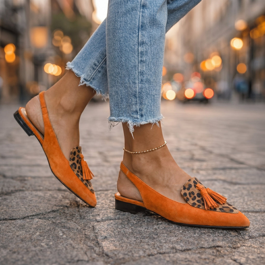Primer plano de mules bicolores elegantes, mostrando los pompones decorativos y la punta afilada, ideal para mujer.