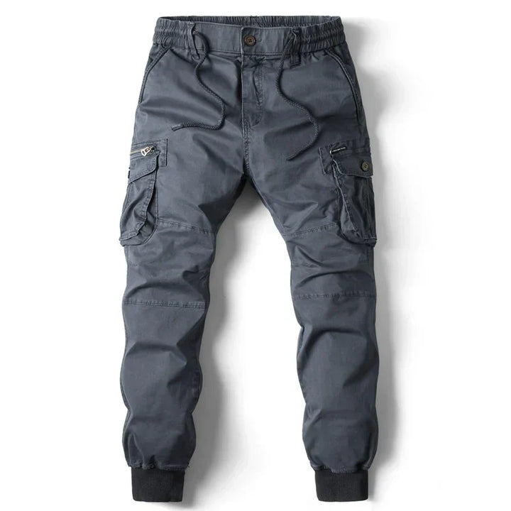 Hombre vistiendo pantalón jogger cargo ARLO gris en ambiente urbano, mostrando versatilidad y estilo casual.