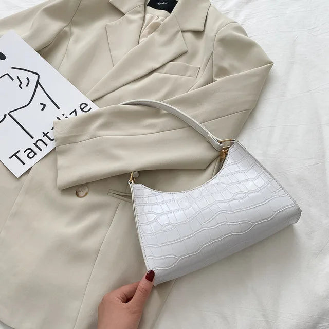 Accesorio de moda femenina: Bolso de hombro de piel de cocodrilo brillante y sofisticado.