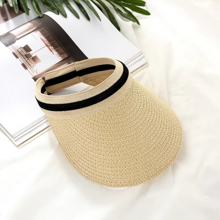 Persona usando sombrero visera unisex de paja con protección UV y ala ancha en un día soleado de playa.