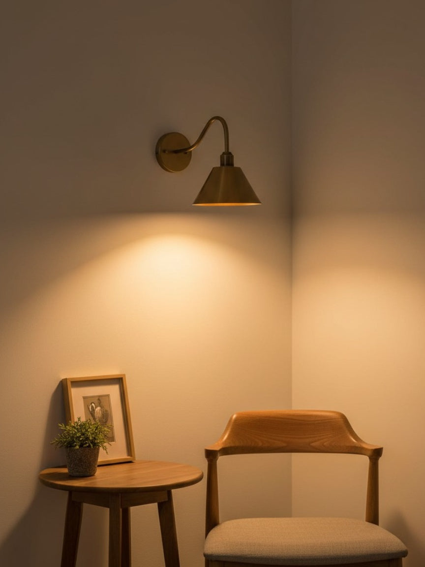 Aplique moderno de latón y negro, diseño cónico, iluminación interior sofisticada.