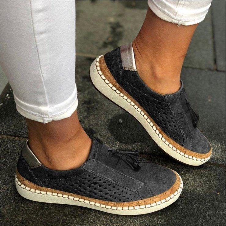 Detalle de zapatos slip-on para mujer, con diseño perforado y borlas, suela cómoda de corcho para verano.
