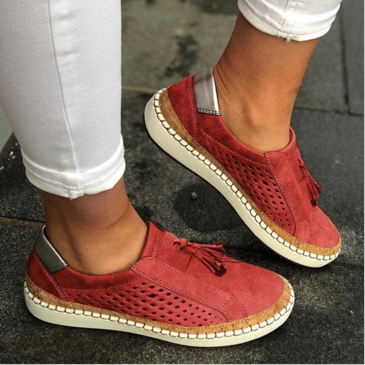 Mujer luciendo zapatos slip-on casuales perforados con borla y suela de corcho, perfectos para looks de verano.