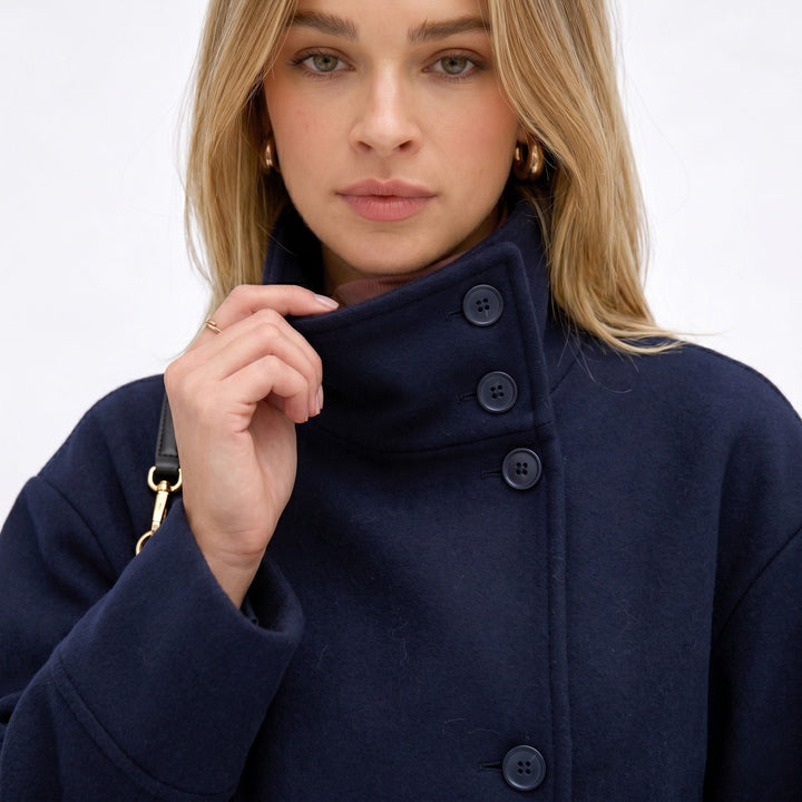 Chaqueta azul oscuro de mujer, corta, cuello alto, con botones y manga larga para un look casual moderno.