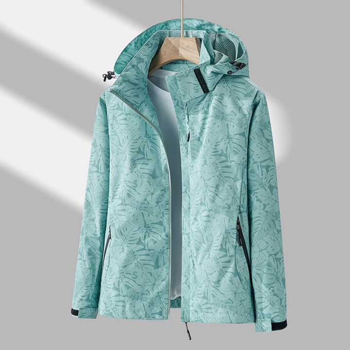 Mujer en el exterior con chaqueta cortavientos impermeable y capucha. Protección ligera para deporte, senderismo o casual.