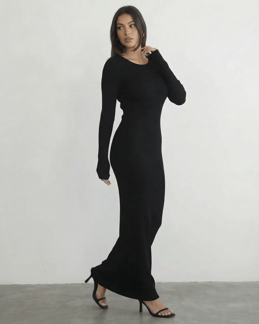 Mujer luciendo vestido maxi negro de manga larga con elegante espalda abierta. Ropa de fiesta.