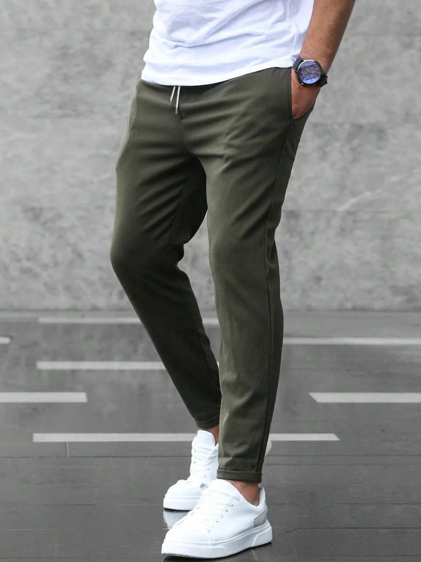 Hombre usando pantalón deportivo ajustado en entorno urbano, destacando flexibilidad y estilo moderno.