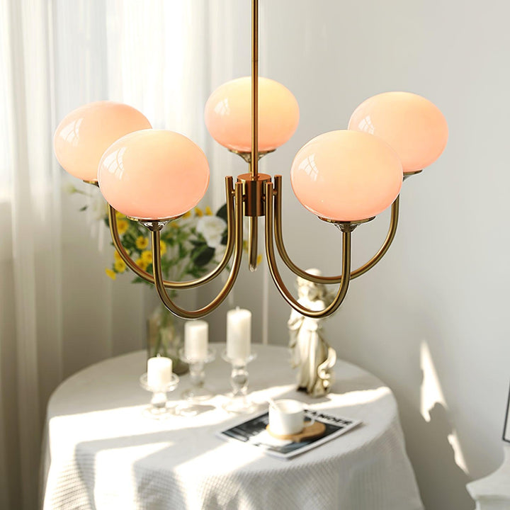 Iluminación interior con araña Alora Marshmallow, cristal rosa y dorado, estilo moderno.