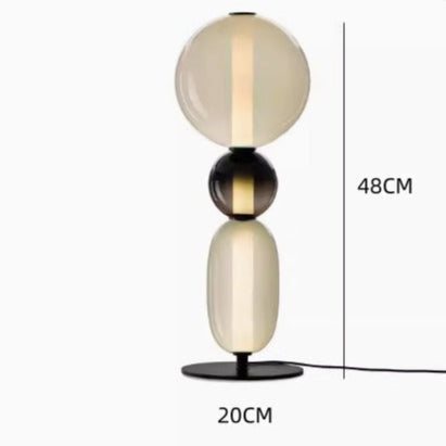Moderna lámpara de mesa LED regulable, con acabados en negro y latón, eficiencia energética.