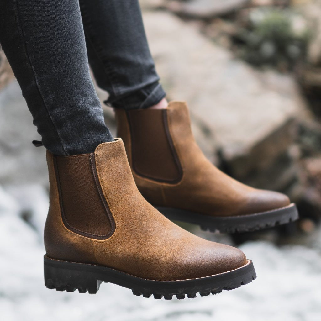 Primer plano de botines Chelsea de piel lisa para mujer, destacando suela track gruesa y elásticos laterales.