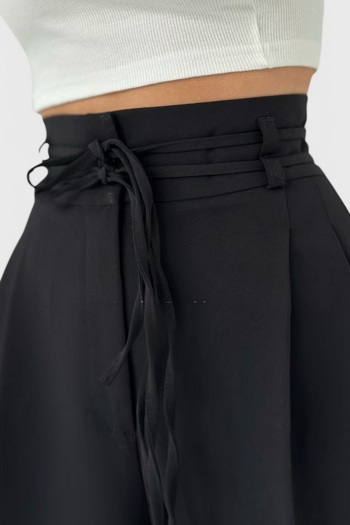 Detalle de los cordones en la cintura de pantalones anchos de mujer, resaltando el diseño fluido.