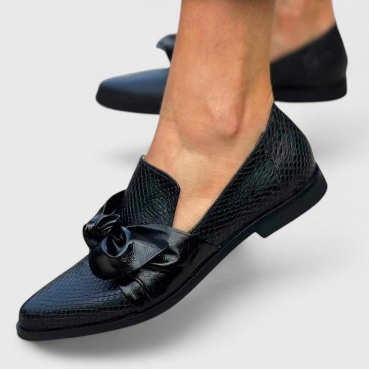 Detalle de lazo decorativo en mocasines elegantes de mujer negros. Calzado femenino de moda con estilo casual.