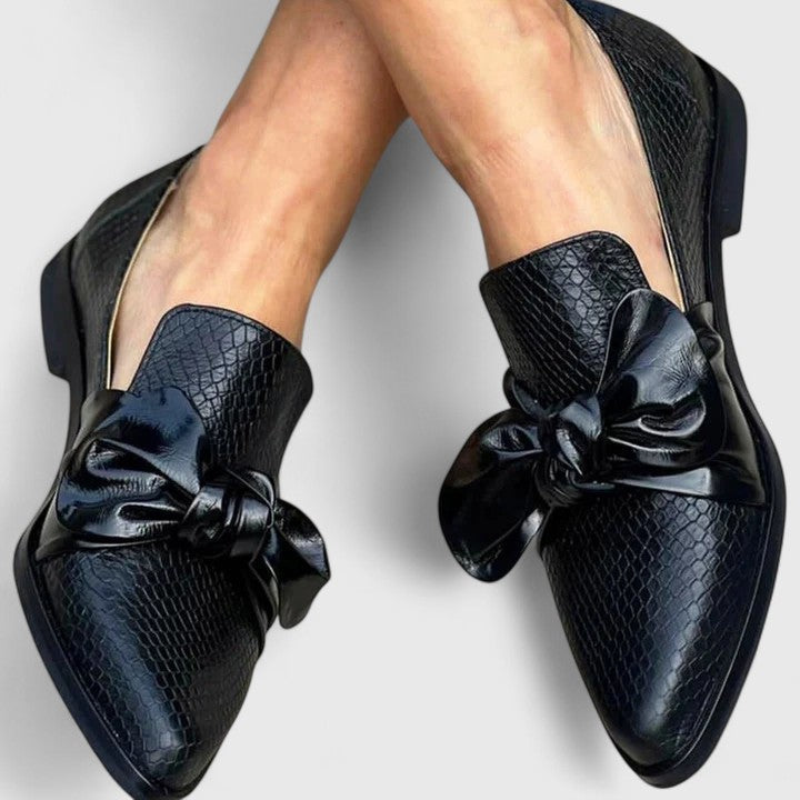 Mocasines elegantes negros de mujer con diseño sin cordones. Calzado femenino cómodo con lazo para estilo casual elegante.