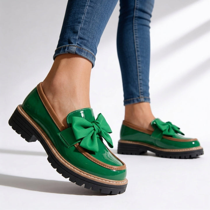 Zapato mocasín de charol para mujer, color negro, con detalle de lazo. Diseño de suela gruesa que aporta confort y estilo.