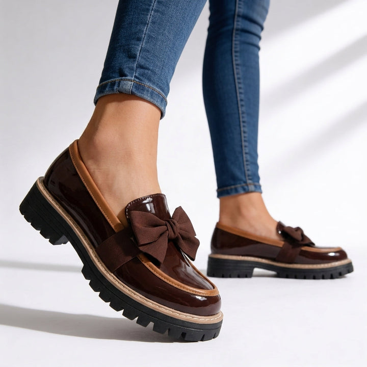 Mocasines de mujer elegantes, charol negro, con lazo frontal y suela gruesa. Zapatos de moda para looks casuales y sofisticados.