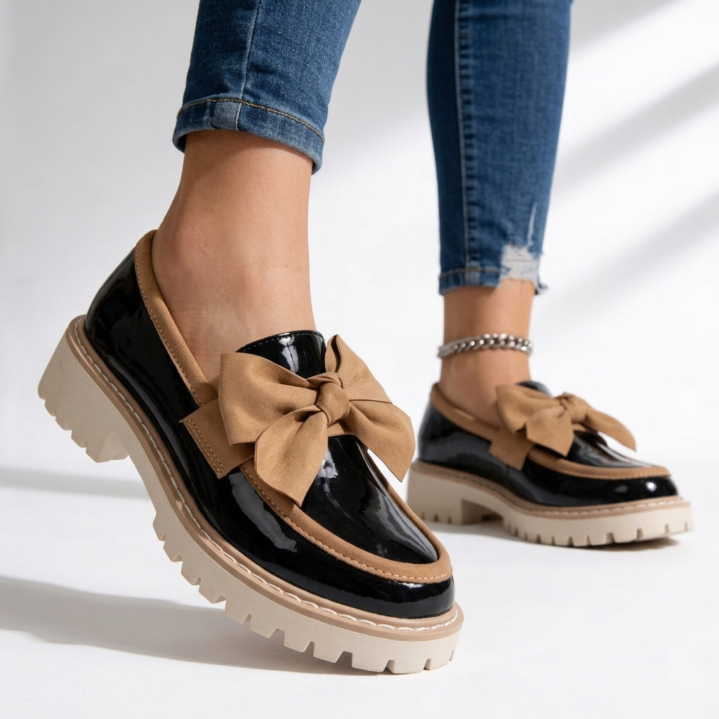 Mocasines de mujer en charol negro con lazo decorativo, suela gruesa y plataforma. Ideales para otoño, estilo casual elegante.